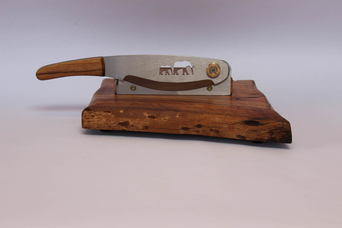 Biltong cutter with a stainless steel blade mounted on a Wild Olive board